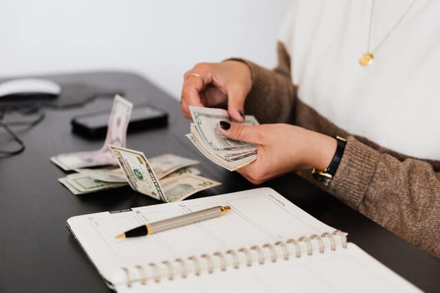 Home crop payroll clerk counting money while sitting at table